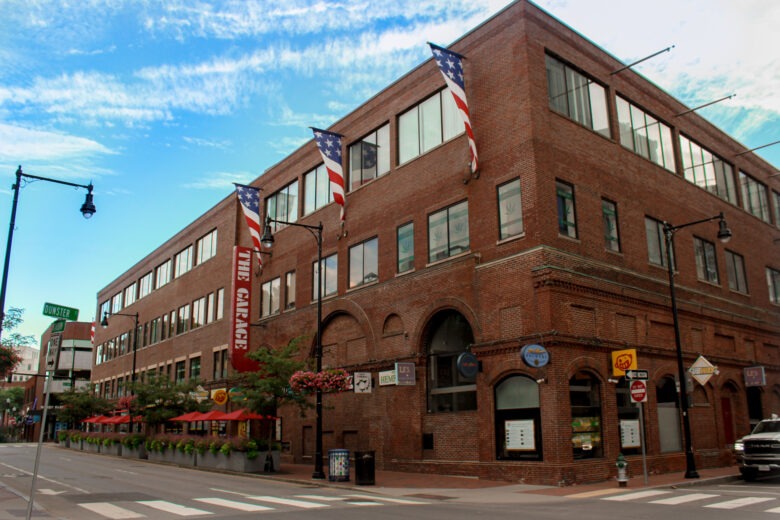 Historic red brick building, "The Garage," adorned with American flags, located on a city street. The image showcases a vibrant urban atmosphere.